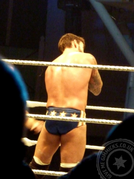 man in blue underwear standing in a cage on top of a ring