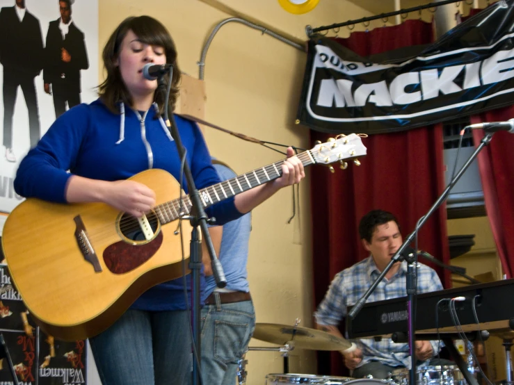 a man playing guitar with a woman singing in front of him