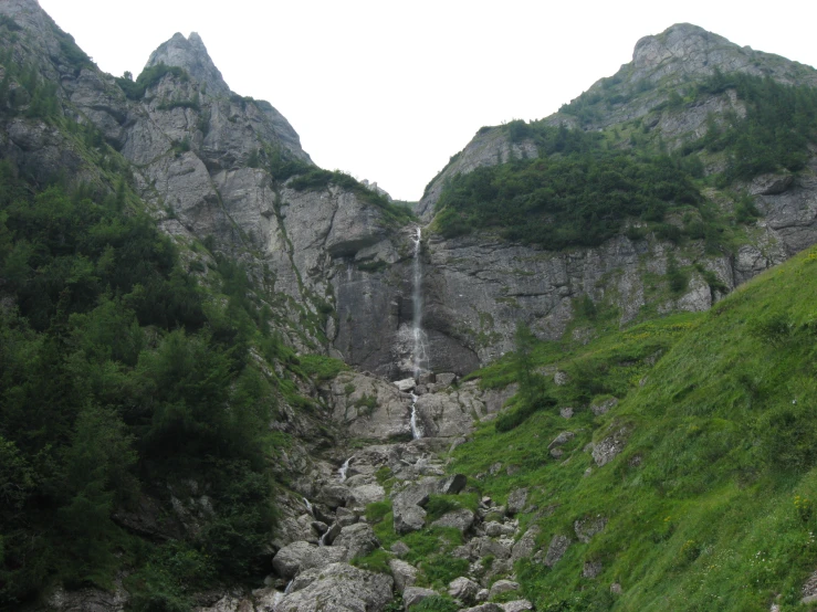 a waterfall surrounded by lush green vegetation in a mountain range