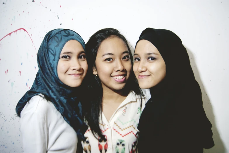 a group of three women smile while taking a po