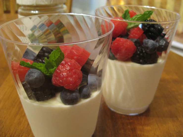 two dessert dishes with strawberries, raspberries and blueberries in them