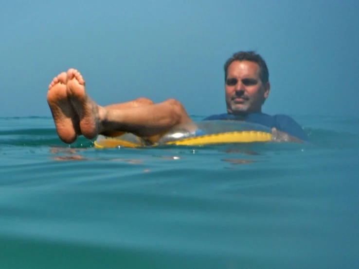 a man swimming on a yellow and grey surf board