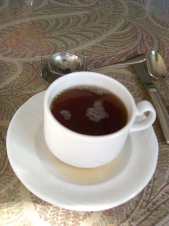 a white cup filled with coffee sitting on a table