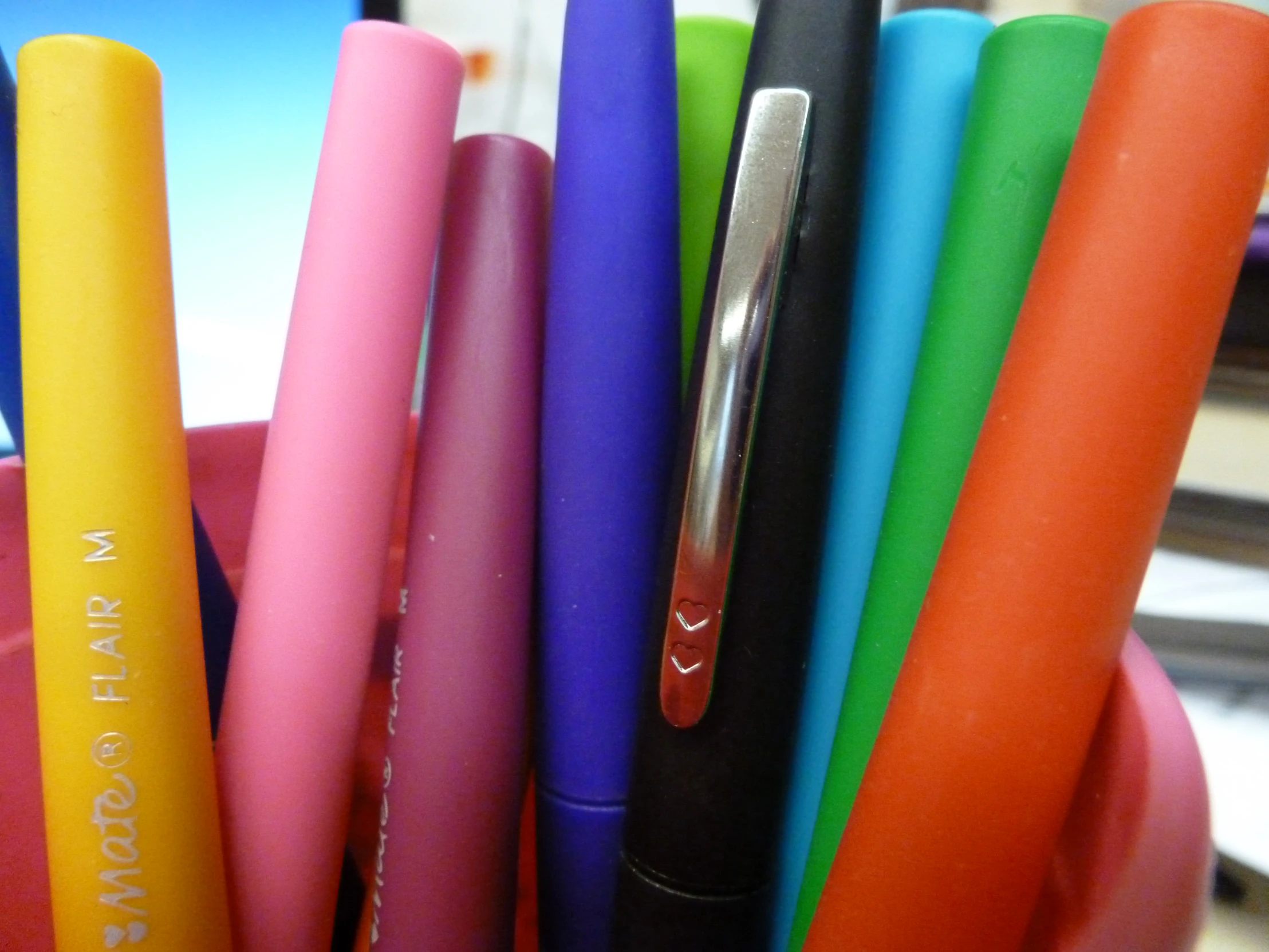 pens, including pink, orange, yellow, green, red, and purple in a cup