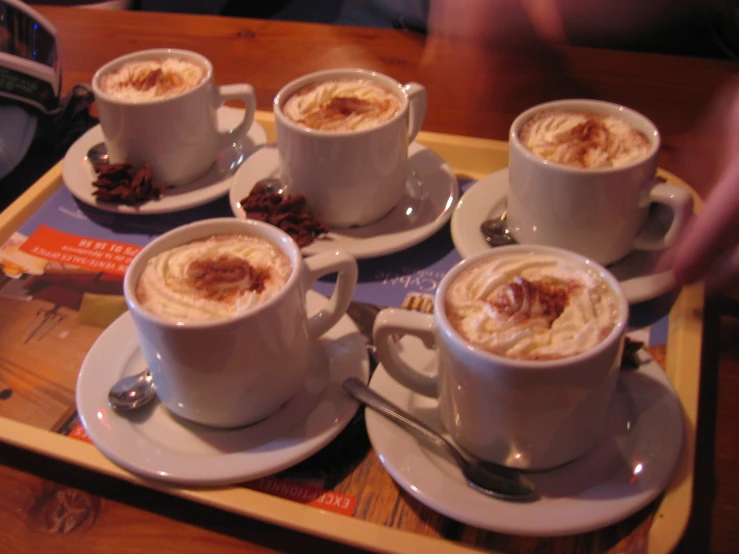 several cups of drink sit on a wooden tray