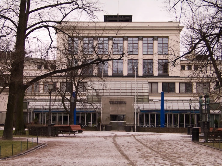 a large building with windows and benches near trees