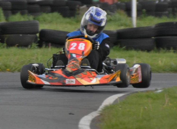 a man sitting on top of a orange race car