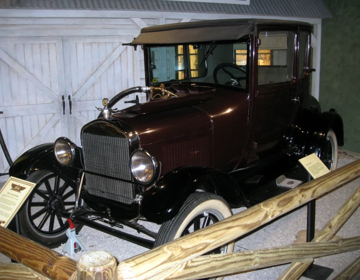 an antique car in a garage parked next to a door