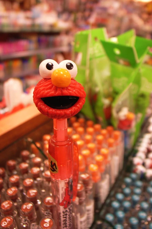a sesame character figurine atop a top of a tall red pen