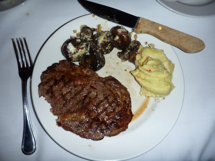 a white plate topped with meat, vegetables and potatoes