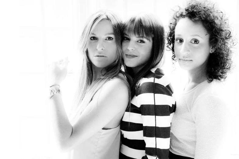 three girls standing near each other and pointing at the camera