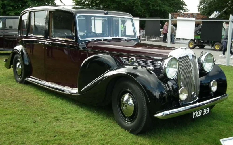 an old model black car on display in a grass field