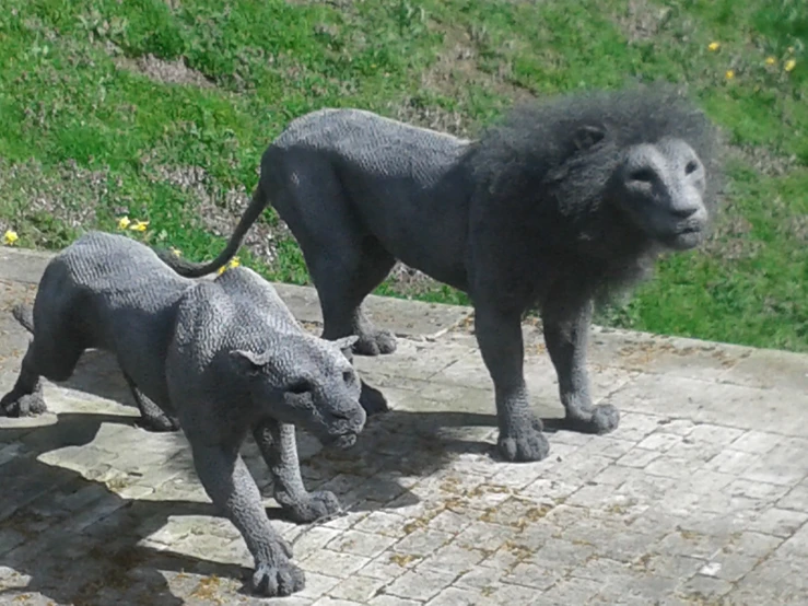 two statues of lions are sitting on a brick sidewalk