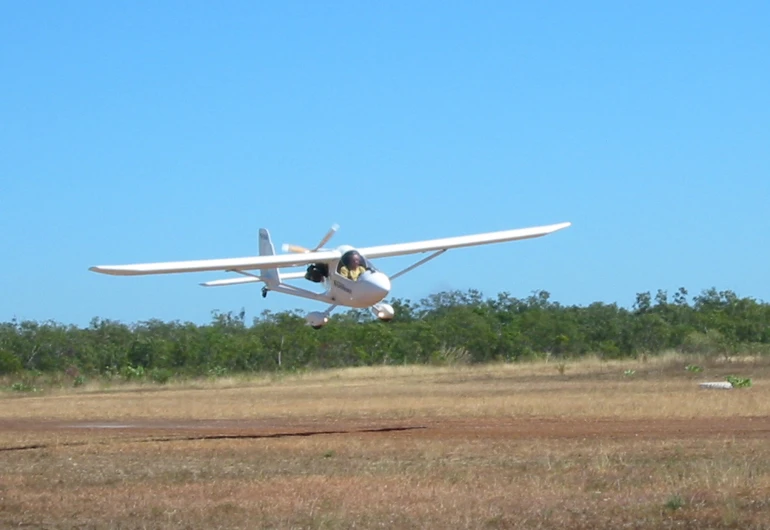 the plane is flying low over the dirt field