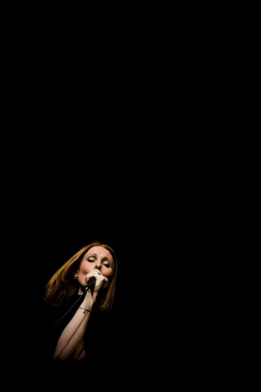 a woman standing in the dark holding a microphone