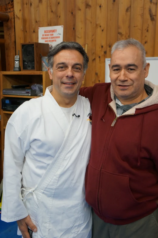 two men standing together wearing white jackets and posing for a picture