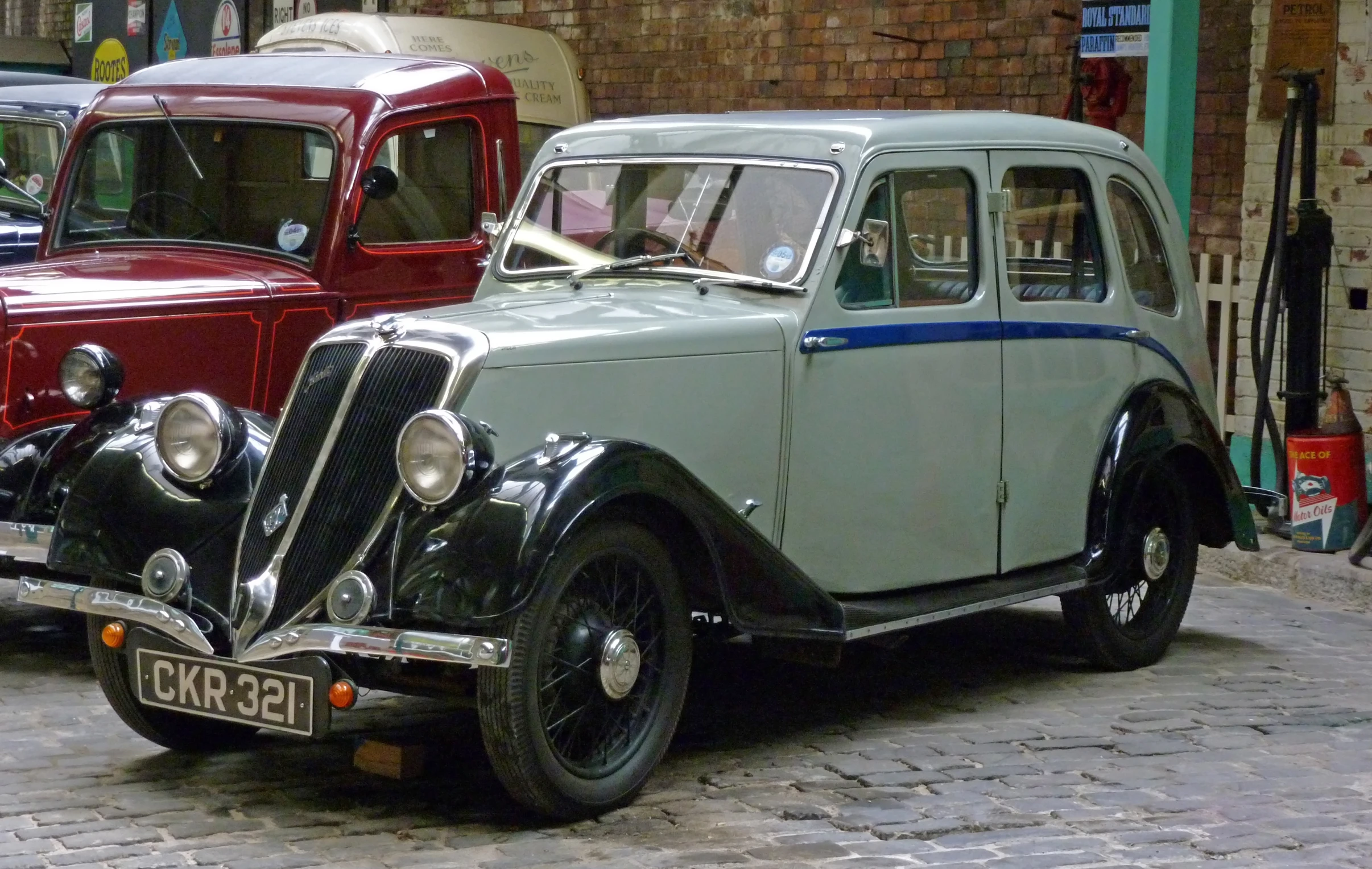 a classic car sitting on the street surrounded by other old cars