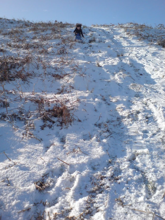 snow covered ground with man and child walking up slope