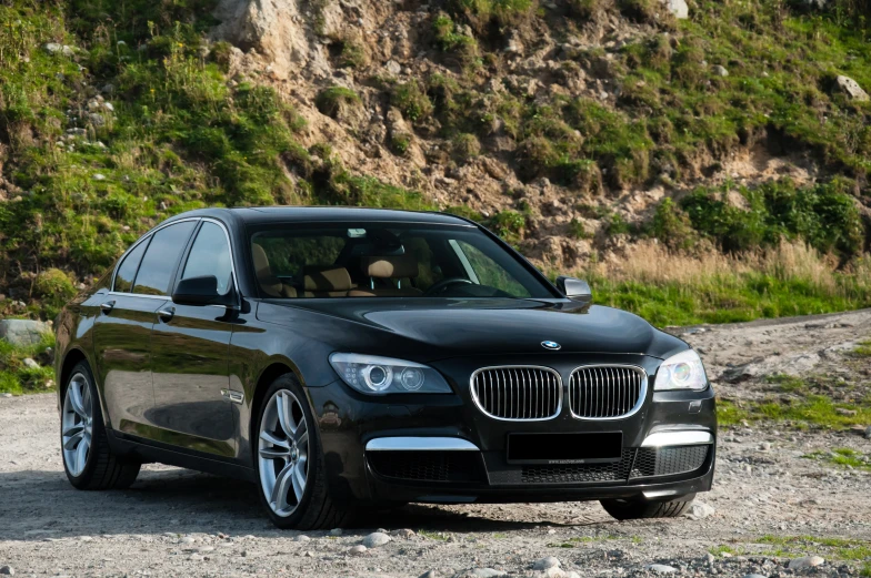 the front view of a black bmw parked in a dirt lot