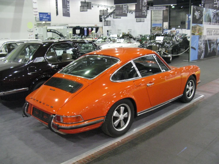 an orange porsche is shown in the middle of a car show