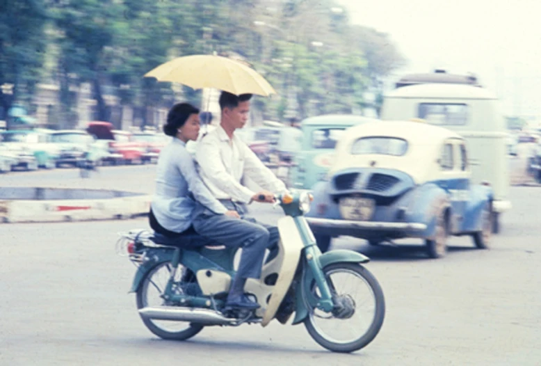 two men riding a motor bike on the street