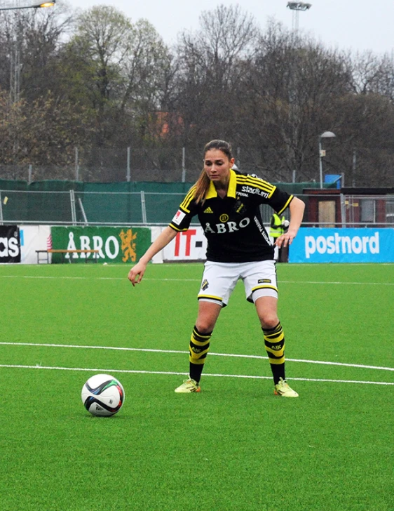 girl playing soccer in a black and yellow uniform