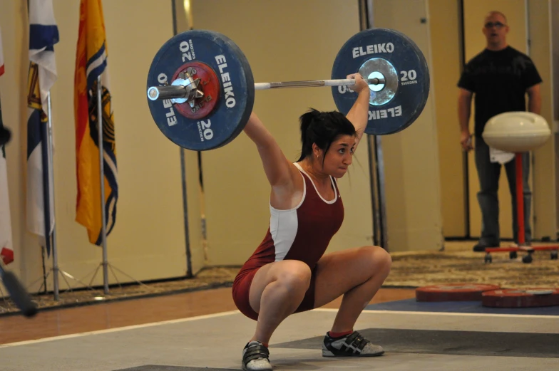 a woman kneeling down with a barbell above her head