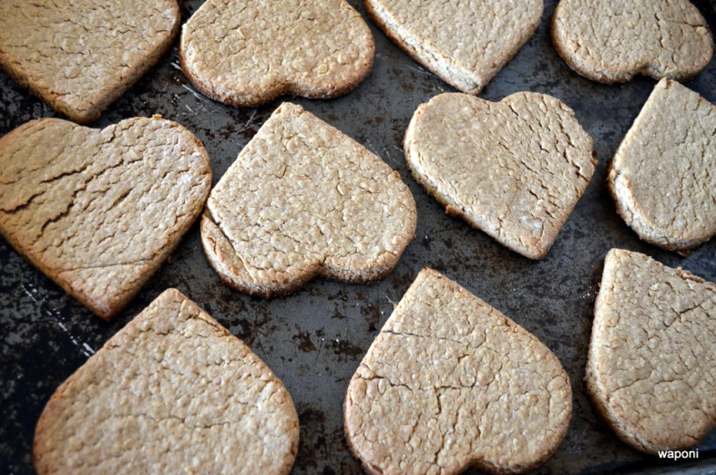 several heart shaped brown cookies are on a pan