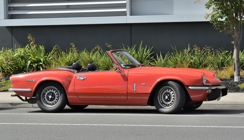 a red convertible sits parked on the side of the road