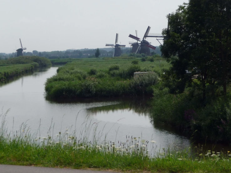 windmills line the shore of a wide canal