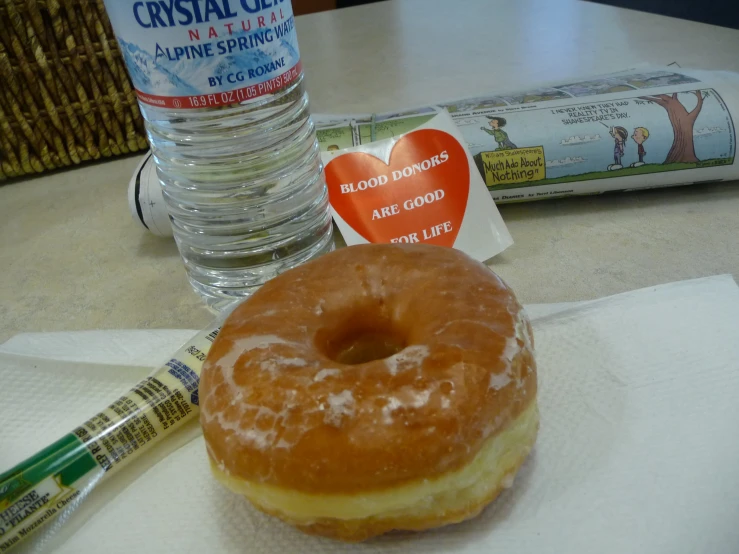 a donut sitting on top of a napkin next to a bottle of water