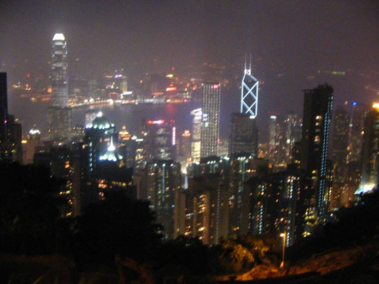 the city lights glow brightly in this view from atop a hill