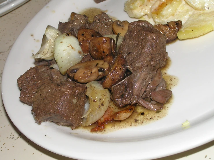 plate with meat and potatoes on it and an onion