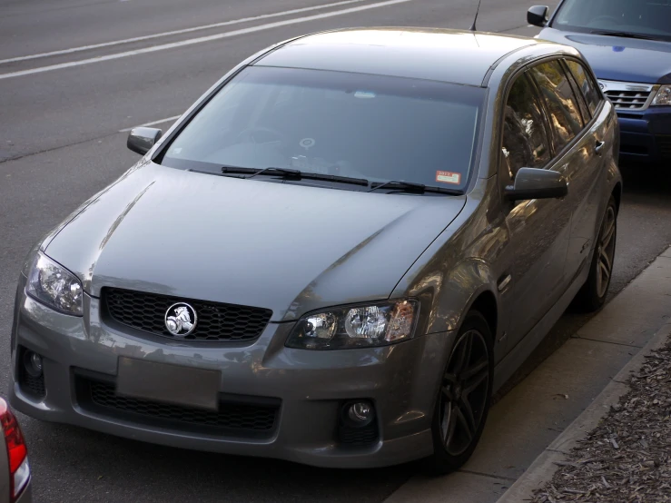 a silver car parked on the street next to a street curb