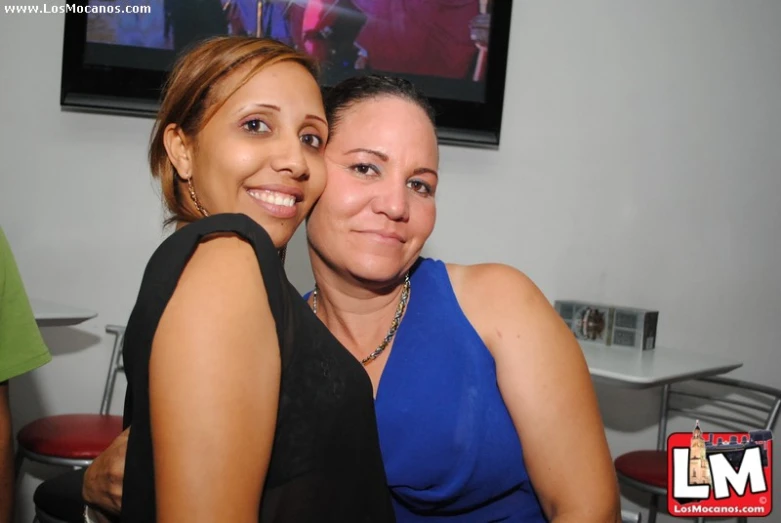 two young women posing together in front of a large tv