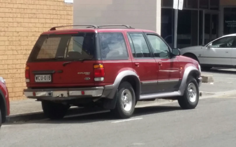 red suv parked on the side of the road near the curb