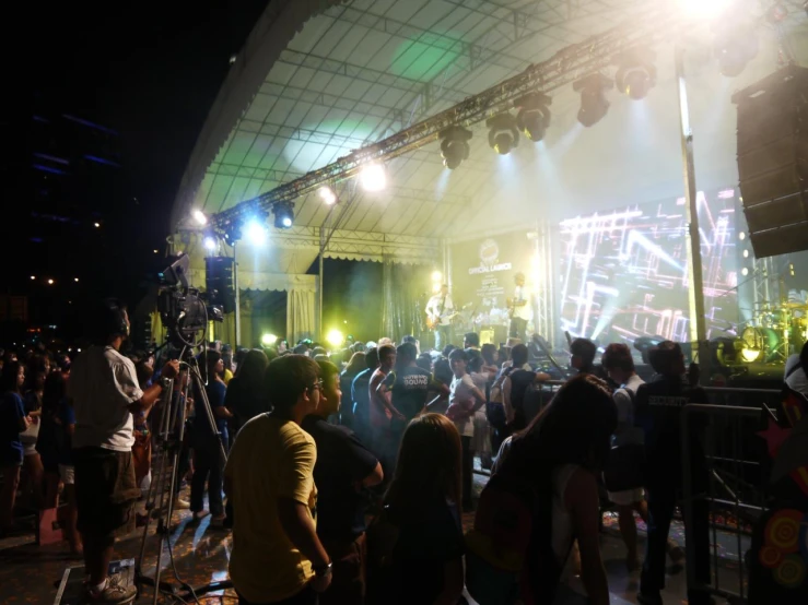 a large group of people gathered around an outdoor concert area