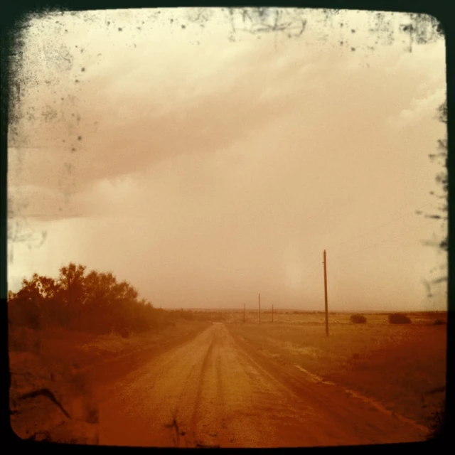 the dirt road near a dry grass field under a cloudy sky