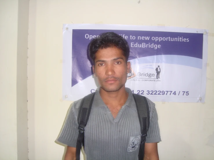 a man standing in front of a wall advertising a new appointments college