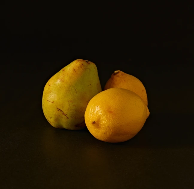 two lemons and one pear are sitting on a table