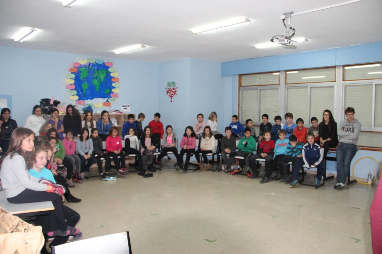 a group of children sitting in front of a classroom full of s