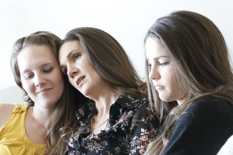 three women looking at soing while sitting down