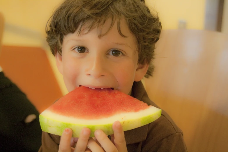 a  wearing a brown shirt is eating a piece of watermelon