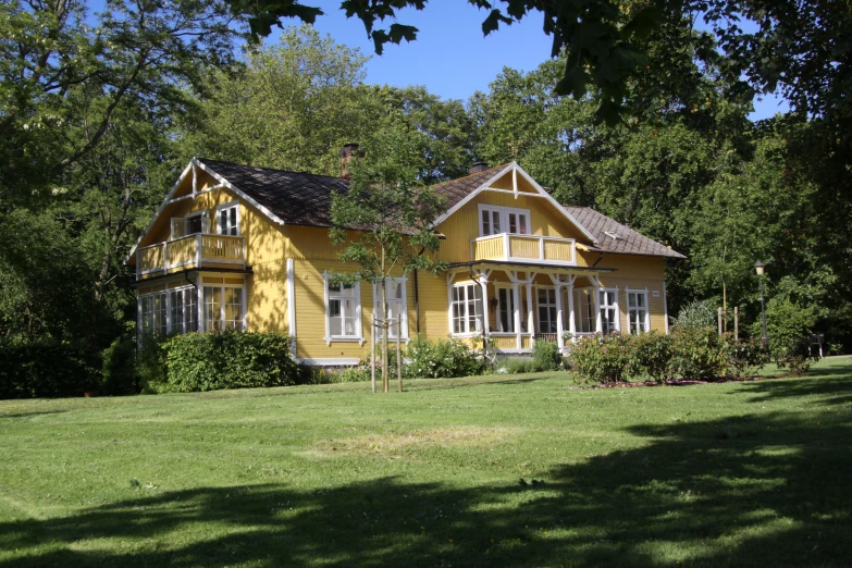 a yellow building in the shade near some trees