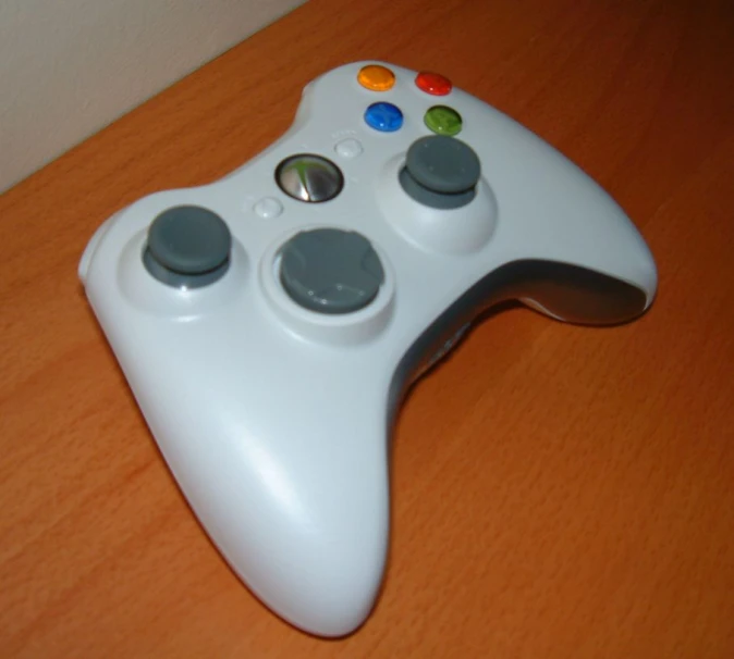 a white video game controller sitting on top of a wooden table