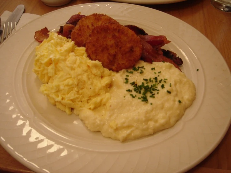 the plate of food has hash browns and eggs on it