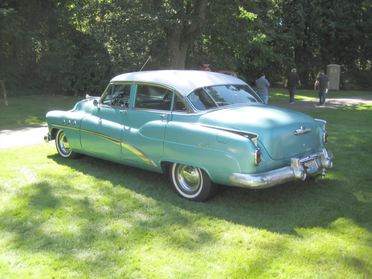 an old blue car in some grass on the lawn