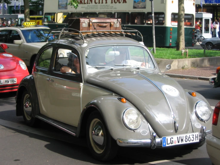 the man is driving his gray vintage beetle through traffic