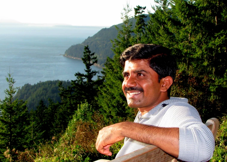 a man standing next to the ocean with trees