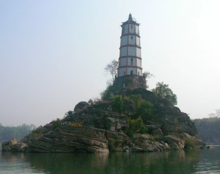 a small lighthouse atop a mountain with water